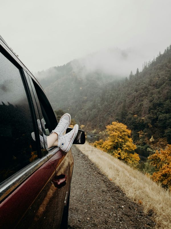 Feet hanging outside a car window in the mountains