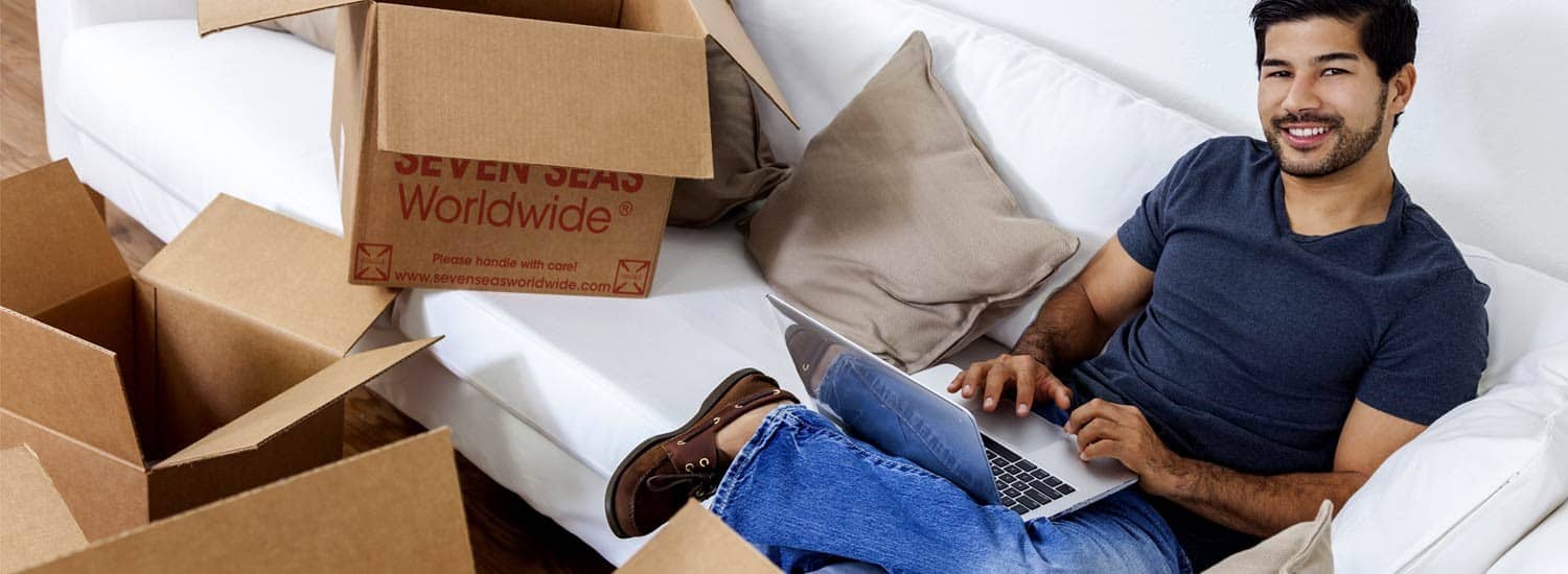 Man checking a laptop while packing boxes