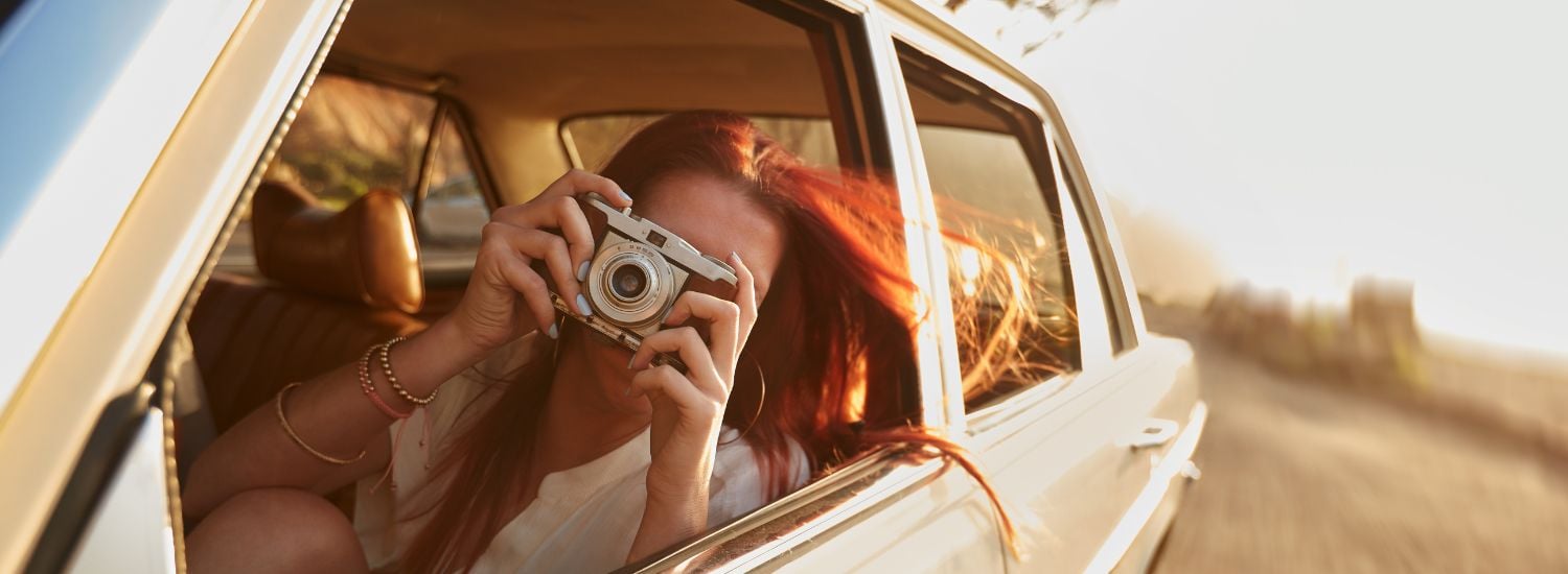 Woman taking a photo sitting in a car